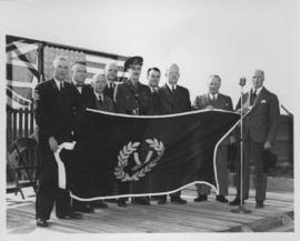 Group of unidentified men and a member of the military holding up a Victory Day flag