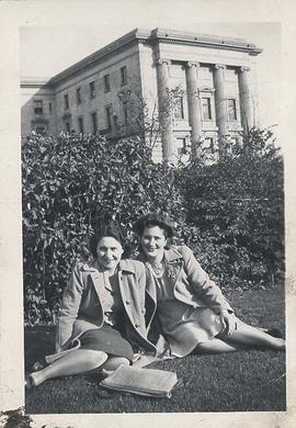 Two students sitting on lawn with Normal School in background