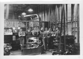 Group of workmen standing behind machinery at Dominion Bridge Company