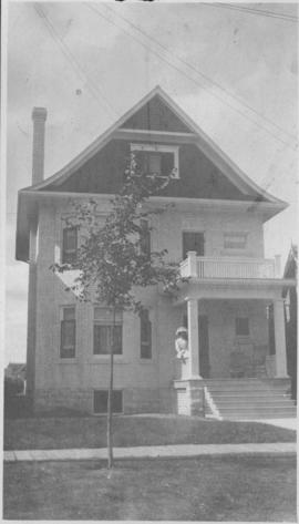 Exterior of home, 146 Spence Street, with woman sitting on porch railing