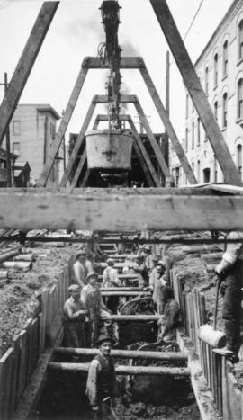 View of men mucking trench for 48-inch diameter Branch 1 aqueduct at Sta. 169+00 on Pacific Avenu...