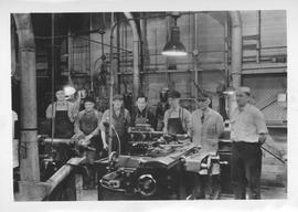 Workmen standing behind machinery at Dominion Bridge Company
