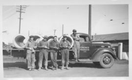Five workers standing in front of truck with a load of concrete forms